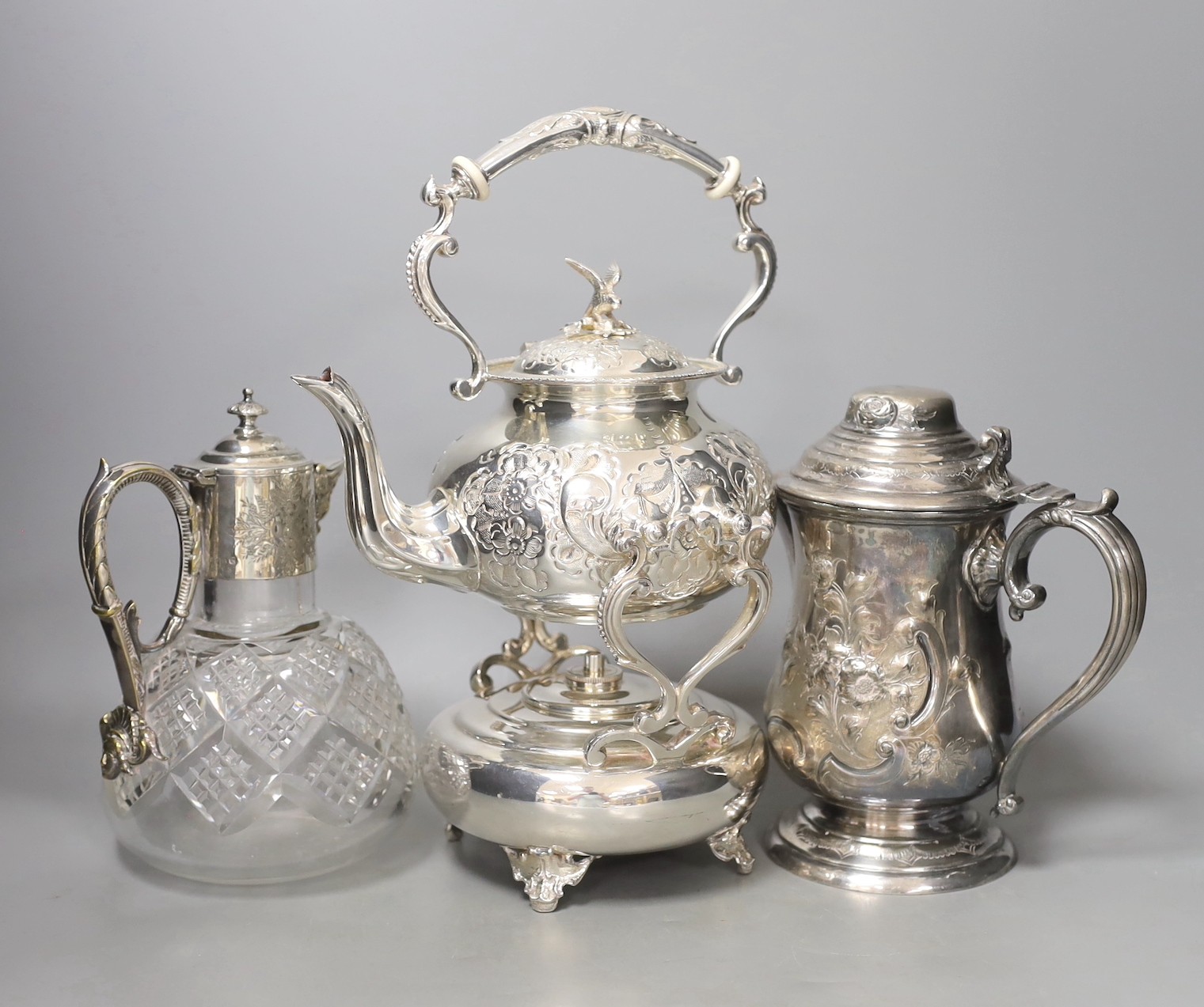 A silver plated tea kettle, burner and stand, ceramic insulators, 33 cm high a mounted claret jug and a tankard